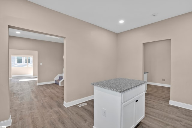 kitchen with white cabinets, light stone countertops, and light hardwood / wood-style flooring