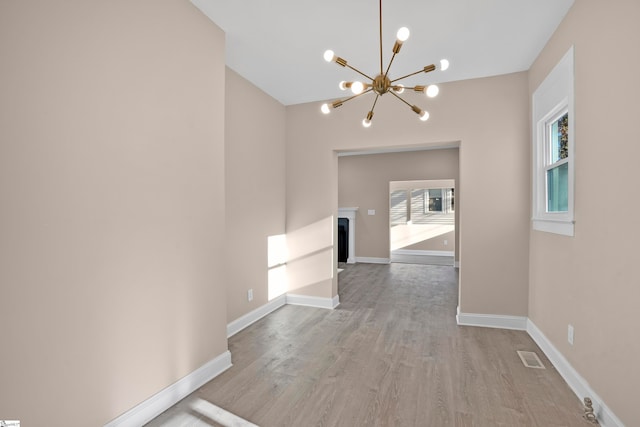 hallway with light hardwood / wood-style flooring and an inviting chandelier