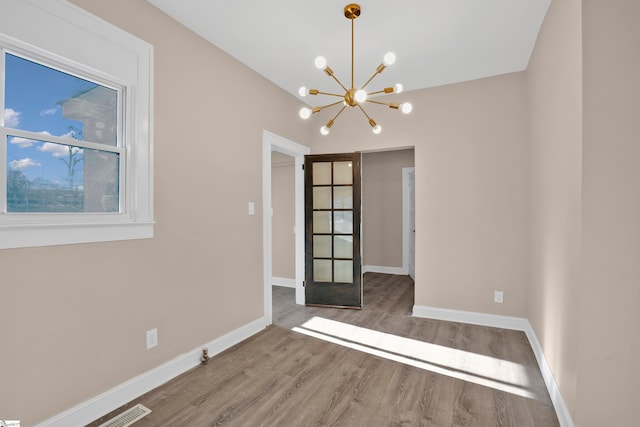 spare room featuring hardwood / wood-style floors, french doors, and a chandelier