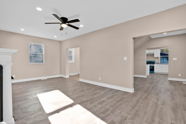 unfurnished living room featuring light wood-type flooring, plenty of natural light, and ceiling fan