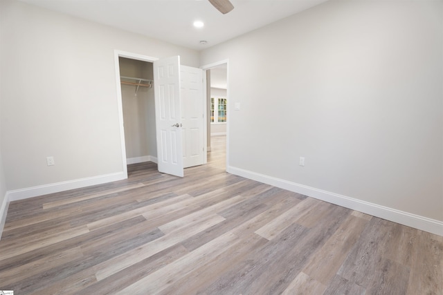 unfurnished bedroom featuring a closet, light hardwood / wood-style floors, and ceiling fan