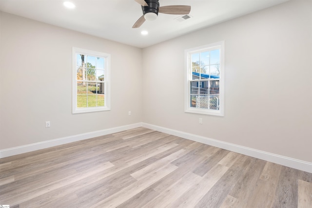 spare room with a wealth of natural light, ceiling fan, and light wood-type flooring