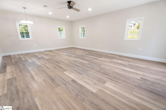 spare room featuring ceiling fan, a healthy amount of sunlight, and light wood-type flooring