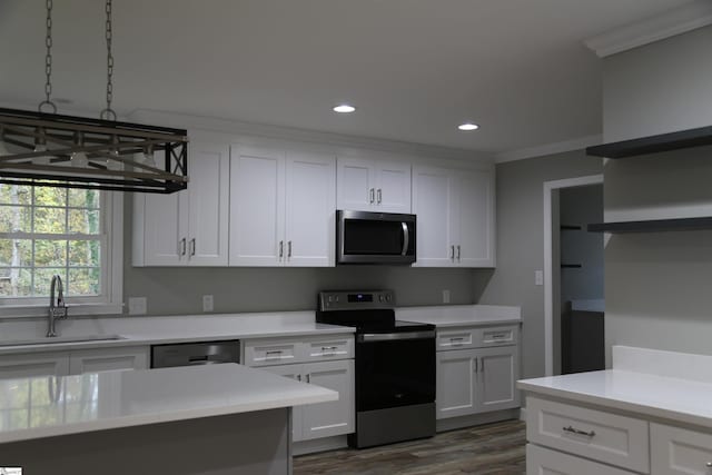 kitchen featuring sink, dark hardwood / wood-style floors, crown molding, white cabinets, and appliances with stainless steel finishes