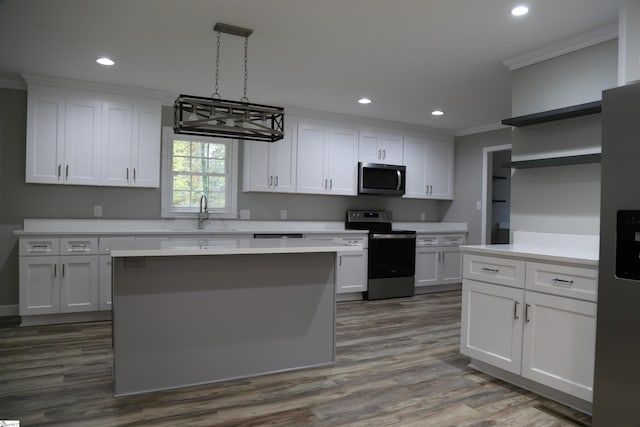 kitchen with crown molding, white cabinetry, stainless steel appliances, and hanging light fixtures