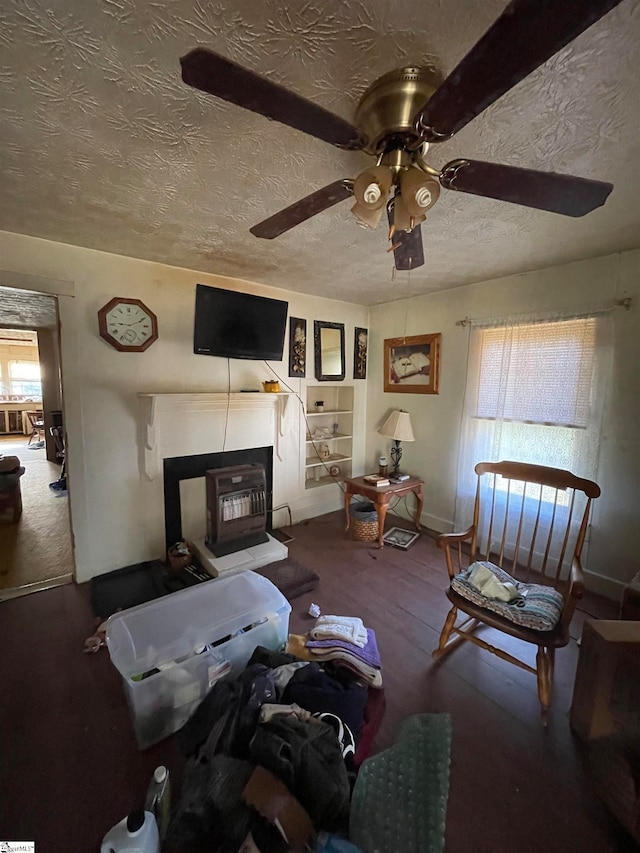 living room with a wood stove, ceiling fan, and a textured ceiling