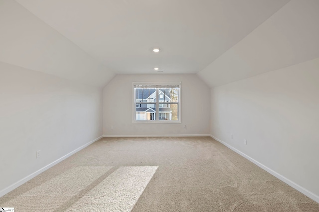 additional living space featuring light colored carpet and lofted ceiling