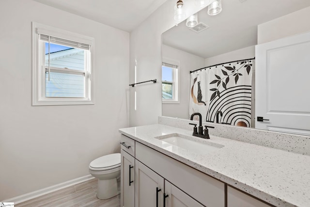 bathroom featuring wood-type flooring, vanity, toilet, and a wealth of natural light