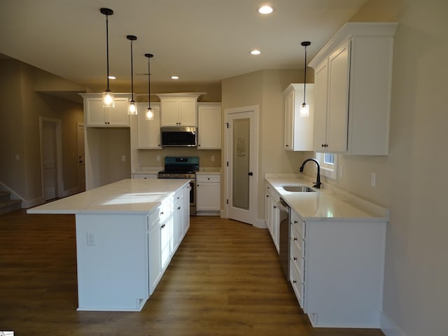 kitchen with stainless steel appliances, sink, white cabinets, a center island, and dark hardwood / wood-style floors