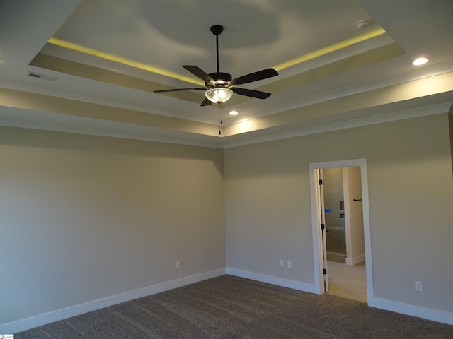 spare room featuring light carpet, a raised ceiling, and ceiling fan