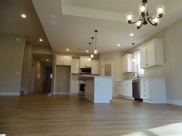 kitchen featuring a center island, an inviting chandelier, white cabinets, hanging light fixtures, and stainless steel appliances