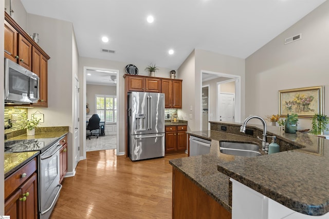 kitchen with sink, stainless steel appliances, tasteful backsplash, light hardwood / wood-style floors, and vaulted ceiling