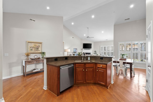 kitchen featuring sink, high vaulted ceiling, stainless steel dishwasher, a kitchen island with sink, and light wood-type flooring