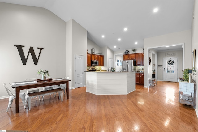 kitchen with tasteful backsplash, light hardwood / wood-style floors, lofted ceiling, and appliances with stainless steel finishes