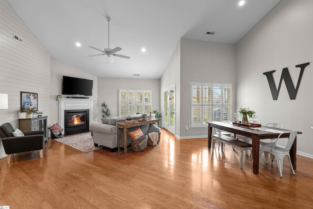 living room with ceiling fan, high vaulted ceiling, and light wood-type flooring