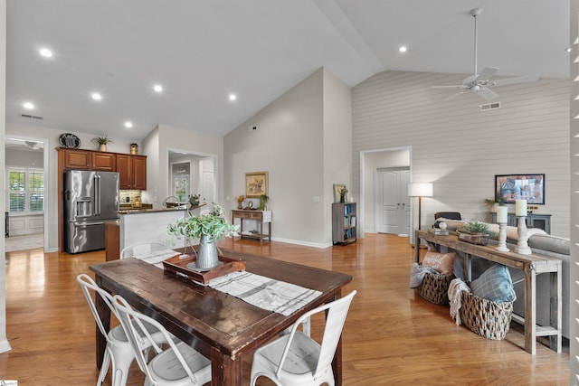 dining space with ceiling fan, light hardwood / wood-style floors, and high vaulted ceiling