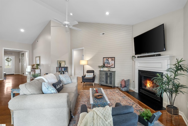 living room with dark hardwood / wood-style floors, ceiling fan, and high vaulted ceiling