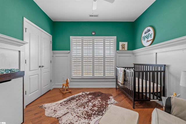 bedroom with ceiling fan, a crib, and light wood-type flooring