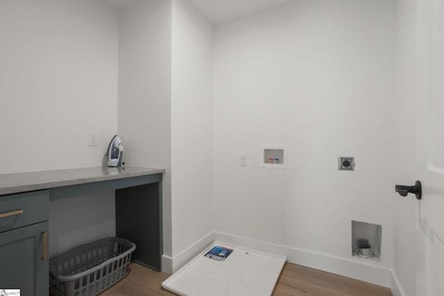 clothes washing area featuring electric dryer hookup, hookup for a washing machine, wood-type flooring, and cabinets