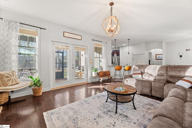 living room featuring french doors, dark wood-type flooring, and a notable chandelier