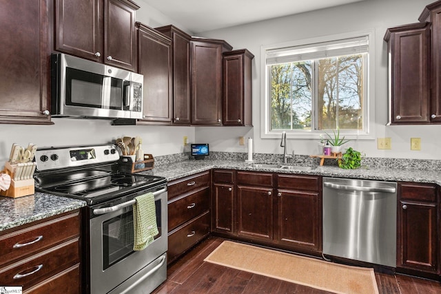 kitchen with light stone countertops, dark hardwood / wood-style flooring, stainless steel appliances, and sink