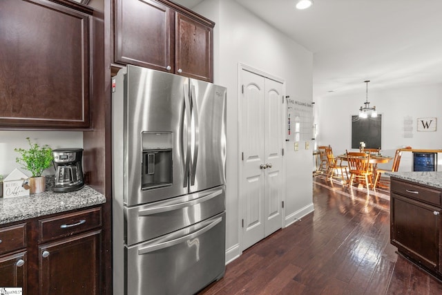 kitchen featuring light stone countertops, hanging light fixtures, beverage cooler, dark hardwood / wood-style flooring, and stainless steel refrigerator with ice dispenser