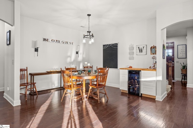 dining space with dark wood-type flooring, beverage cooler, and bar area