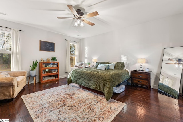 bedroom featuring ceiling fan, dark hardwood / wood-style flooring, and multiple windows