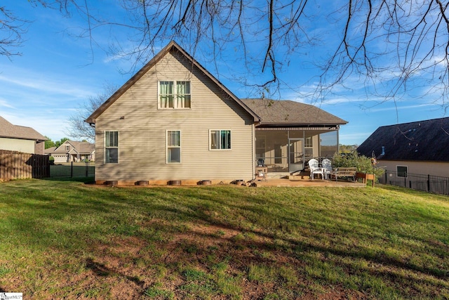 rear view of house featuring a lawn, a sunroom, and a patio area