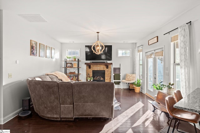 living room with plenty of natural light, dark wood-type flooring, and a brick fireplace