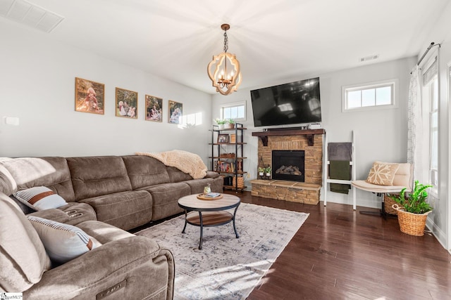 living room featuring a stone fireplace, dark hardwood / wood-style flooring, and a notable chandelier