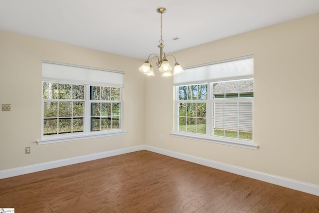 unfurnished room featuring hardwood / wood-style floors and an inviting chandelier