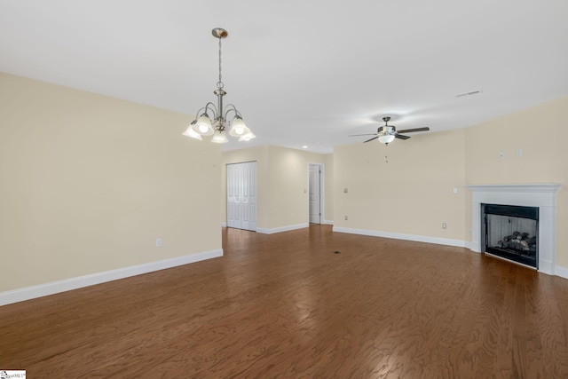 unfurnished living room featuring ceiling fan with notable chandelier and dark wood-type flooring