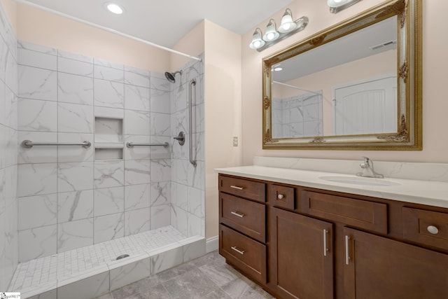 bathroom with a tile shower and vanity