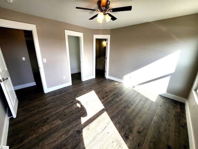 unfurnished bedroom featuring a walk in closet, ceiling fan, connected bathroom, dark hardwood / wood-style floors, and a closet