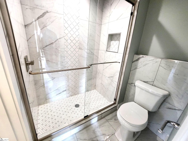 bathroom featuring toilet, tile walls, and a shower with shower door