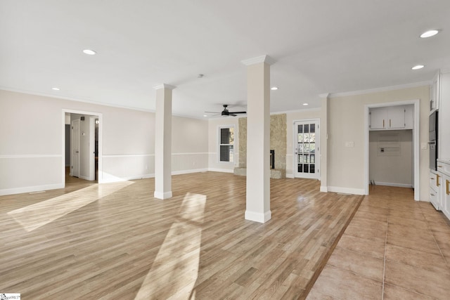 unfurnished living room with ceiling fan, light hardwood / wood-style floors, a fireplace, ornamental molding, and decorative columns