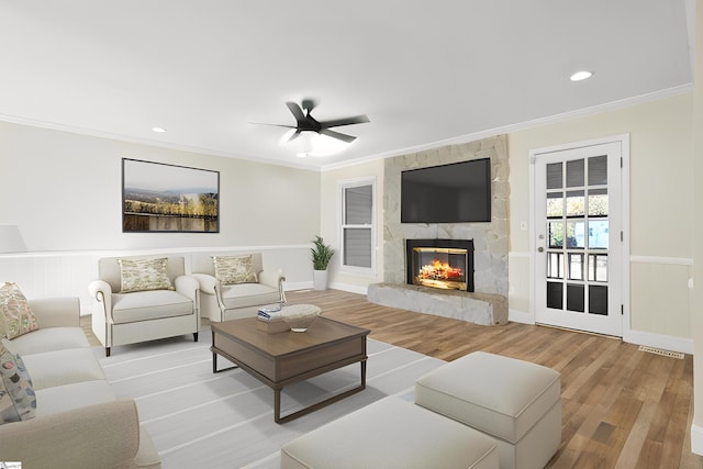 living room with a fireplace, ceiling fan, light wood-type flooring, and crown molding