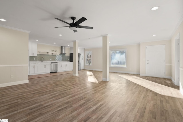 unfurnished living room featuring light hardwood / wood-style floors, sink, ornamental molding, and ceiling fan