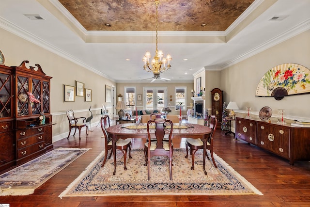 dining area with a tray ceiling, crown molding, ceiling fan with notable chandelier, and dark hardwood / wood-style floors