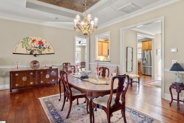 dining area featuring ornamental molding, ceiling fan with notable chandelier, and dark wood-type flooring