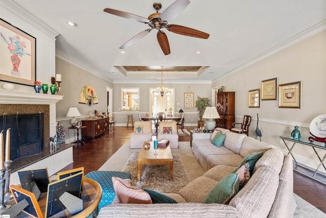 living room with a raised ceiling, ceiling fan with notable chandelier, dark hardwood / wood-style flooring, and ornamental molding