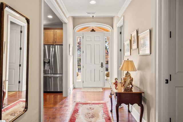 foyer entrance with crown molding and dark wood-type flooring