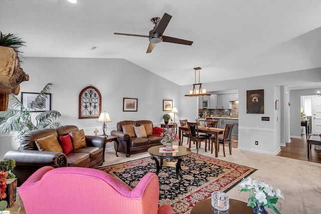 living room with carpet flooring, ceiling fan with notable chandelier, and vaulted ceiling