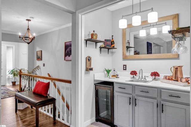 bar featuring hanging light fixtures, crown molding, sink, dark hardwood / wood-style flooring, and beverage cooler