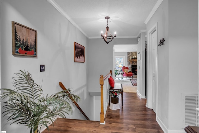 hall featuring a textured ceiling, dark hardwood / wood-style flooring, crown molding, and a notable chandelier