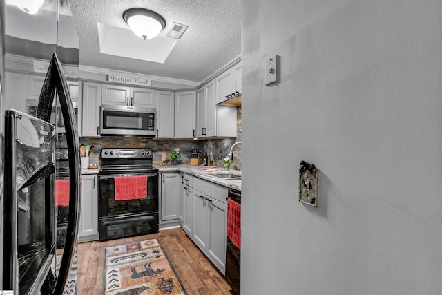 kitchen featuring tasteful backsplash, crown molding, sink, black appliances, and hardwood / wood-style flooring