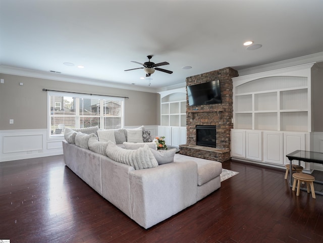 living room featuring a fireplace, ceiling fan, crown molding, and dark wood-type flooring