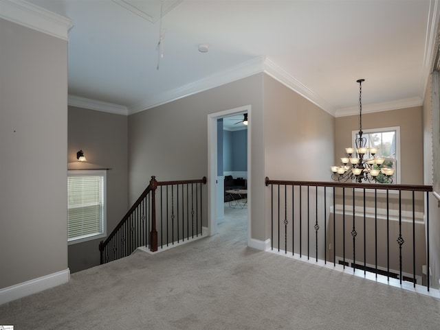 hallway with light colored carpet, a wealth of natural light, crown molding, and a notable chandelier