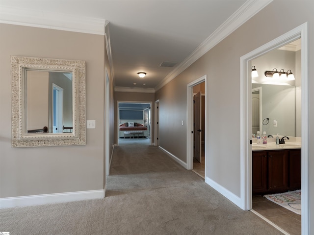 hall with sink, light colored carpet, and ornamental molding